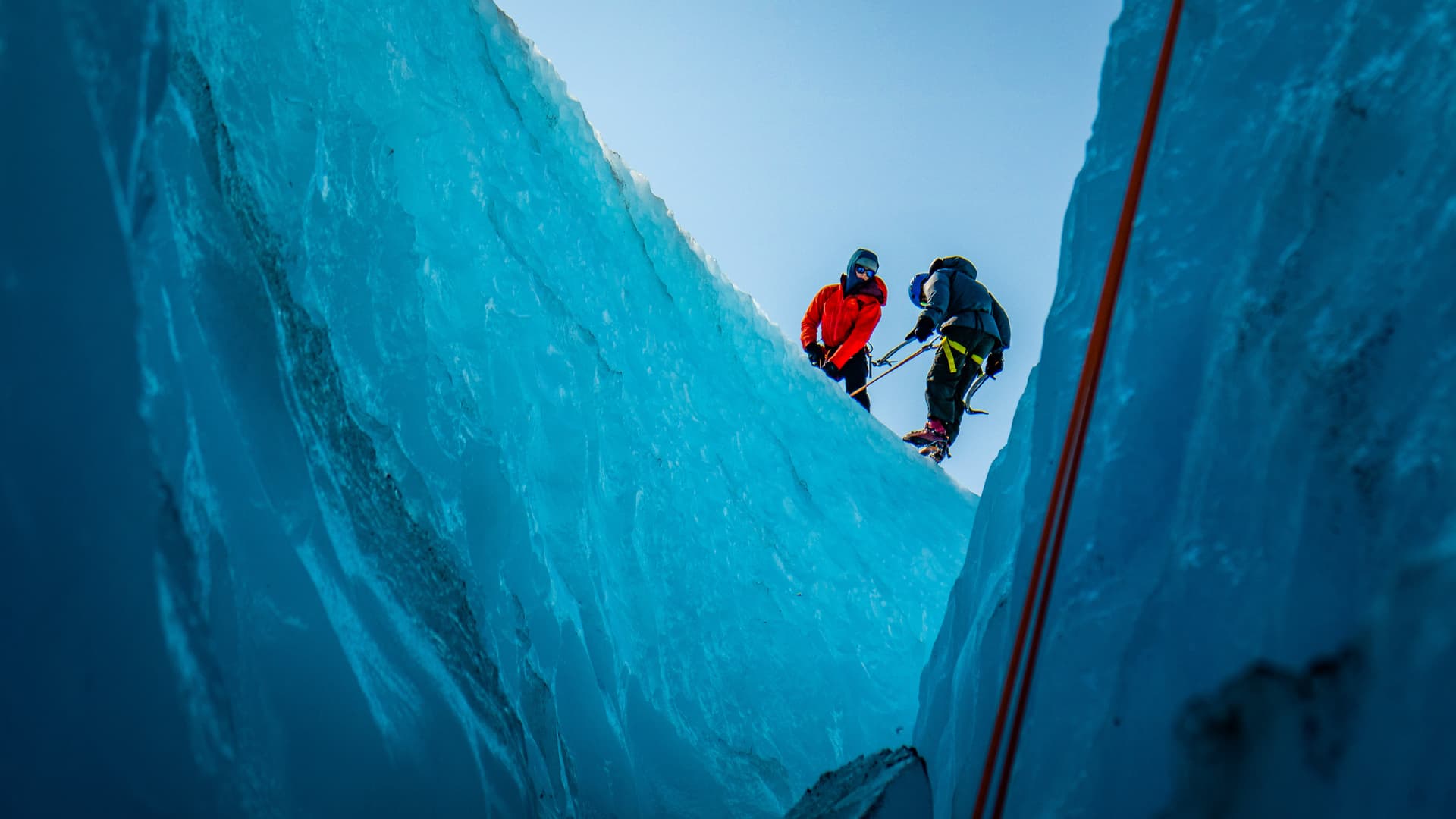 two friends ice climbing on ice wall on holiday